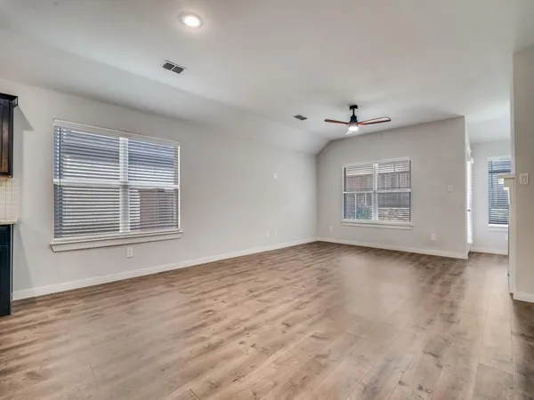 a view of an empty room with a window and wooden floor