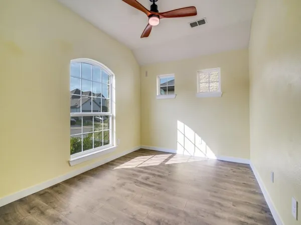 an empty room with wooden floor cabinet and windows
