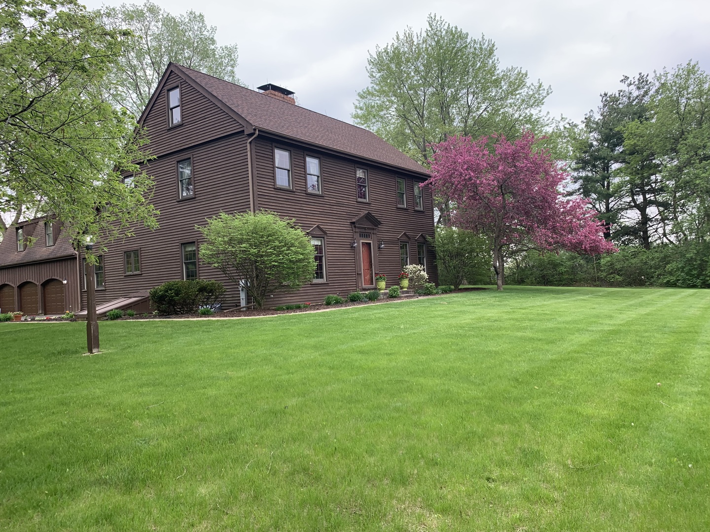 3816 Deep Cut Road Woodstock, IL 60098 - Photo 2 of 32 a brick building sitting in front of a big yard with potted plants and large trees