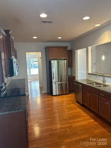 a large kitchen with granite countertop a large counter top and stainless steel appliances