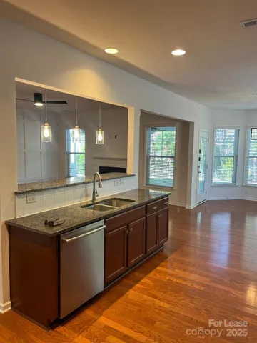 a large kitchen with stainless steel appliances granite countertop a stove a sink and a granite countertops with wooden floor