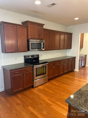 a kitchen with stainless steel appliances granite countertop a stove a sink and a microwave