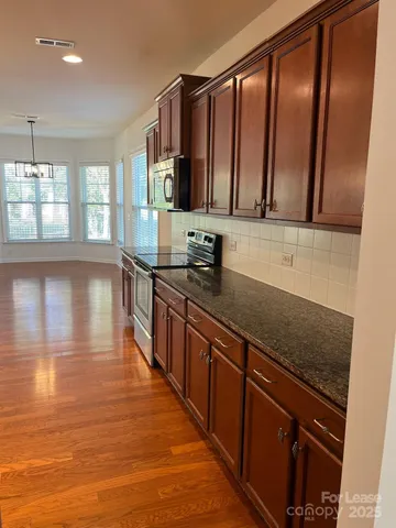a kitchen with stainless steel appliances granite countertop a sink stove and cabinets
