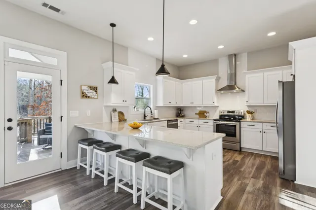 a kitchen with stainless steel appliances granite countertop a stove a sink a refrigerator and a dining table with wooden floor