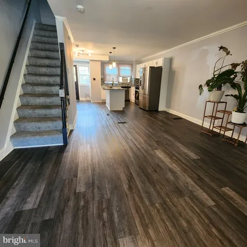 a view of a living room with wooden floor and stairs