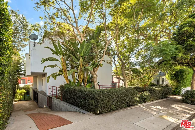 a view of a street with potted plants and large trees