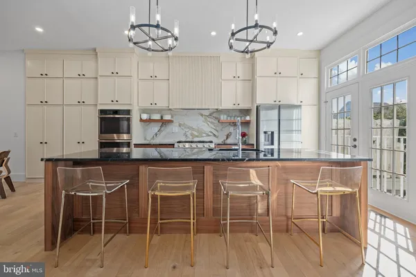 a kitchen with stainless steel appliances granite countertop a refrigerator a sink dishwasher a dining table and chairs with wooden floor