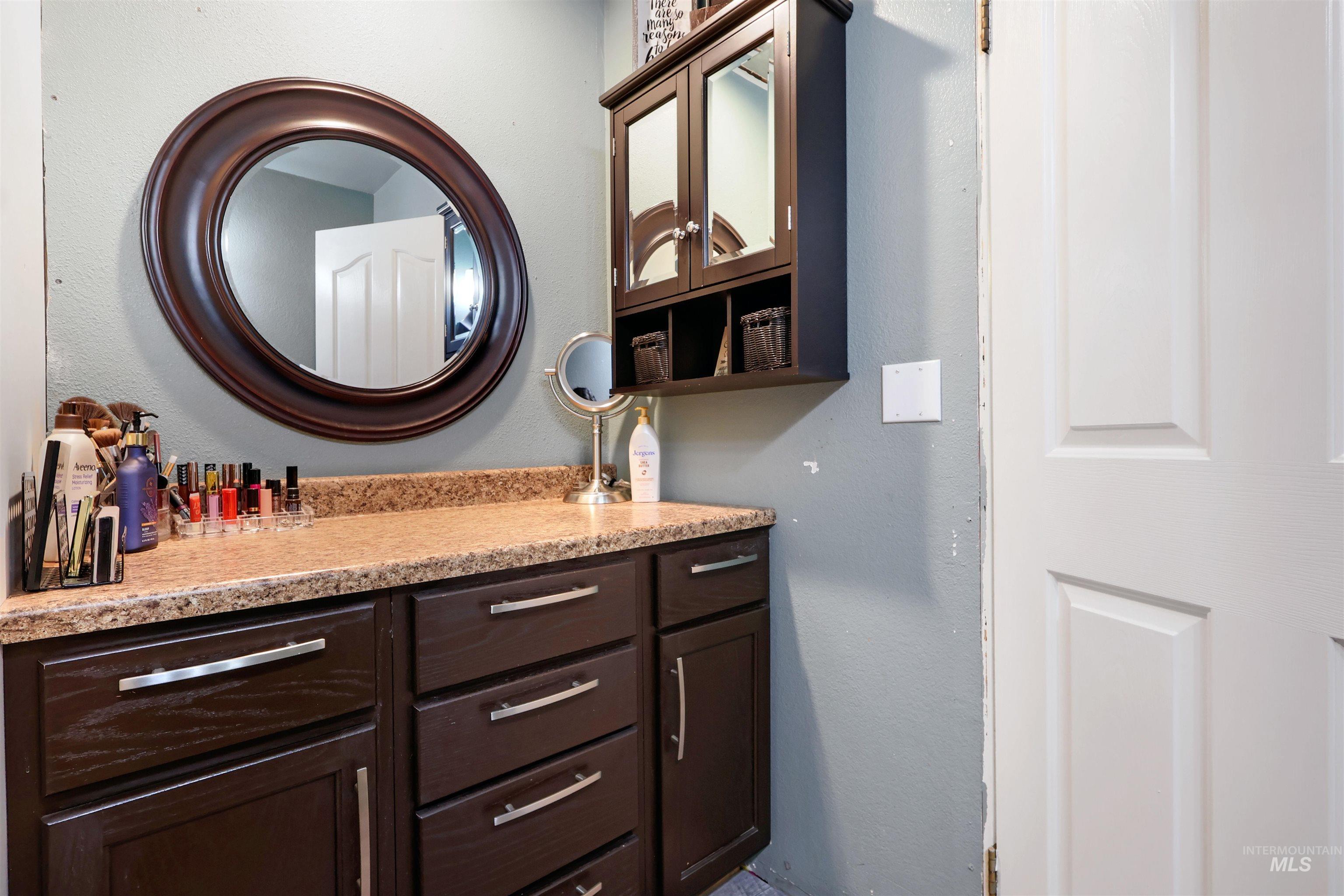 1009 9th Street Rupert, ID 83350 - Photo 14 of 28 Vanity with a speckled countertop, brown cabinetry, and chrome hardware
