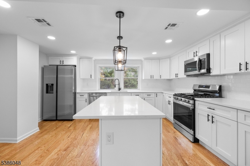 a kitchen with kitchen island a counter top space a sink stainless steel appliances and cabinets