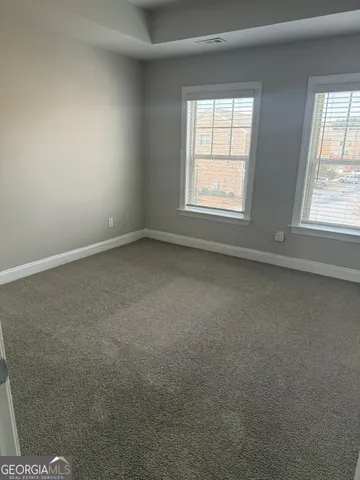 en empty room with windows and chandelier fan