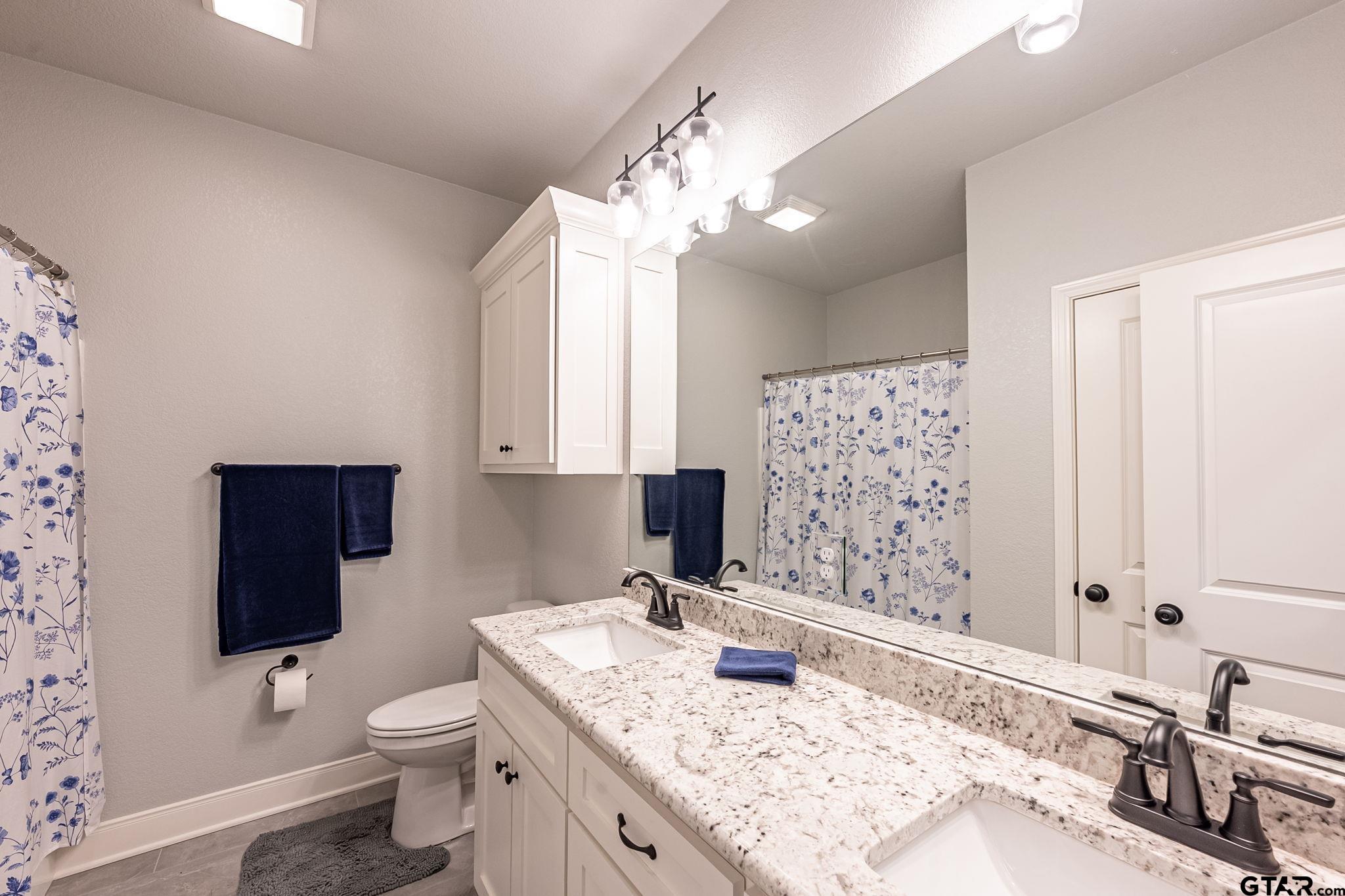 11858 Gillian Court Tyler, TX 75703 - Photo 12 of 24 a bathroom with a granite countertop toilet a sink and a mirror