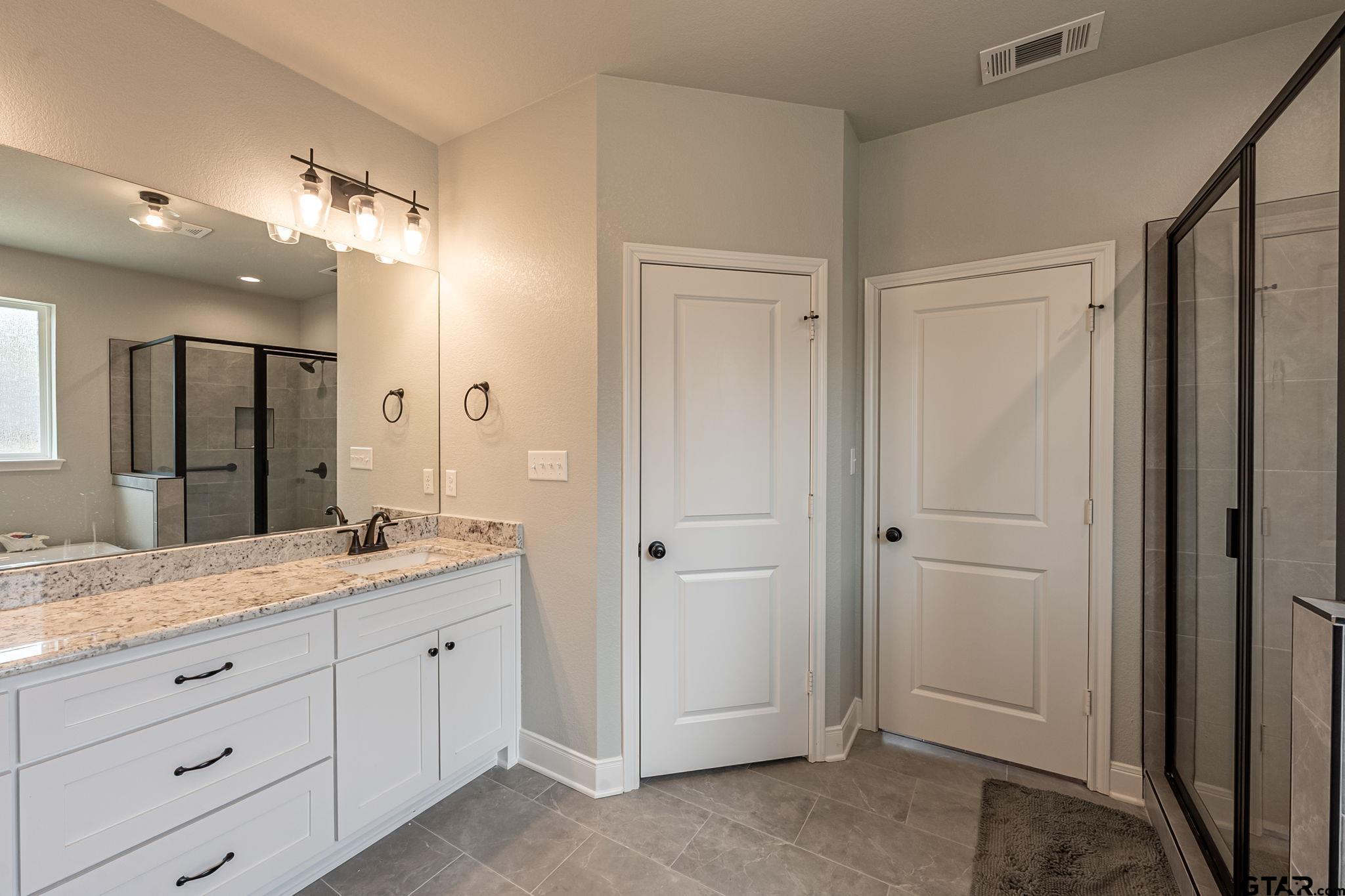11858 Gillian Court Tyler, TX 75703 - Photo 13 of 24 a spacious bathroom with a granite countertop sink mirror and shower