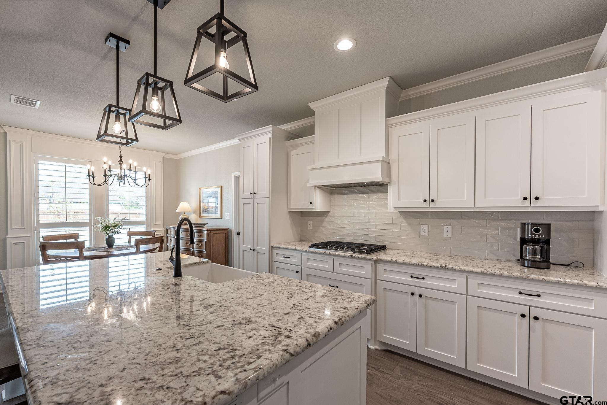 11858 Gillian Court Tyler, TX 75703 - Photo 3 of 24 a kitchen with stainless steel appliances granite countertop a sink a stove and white cabinets