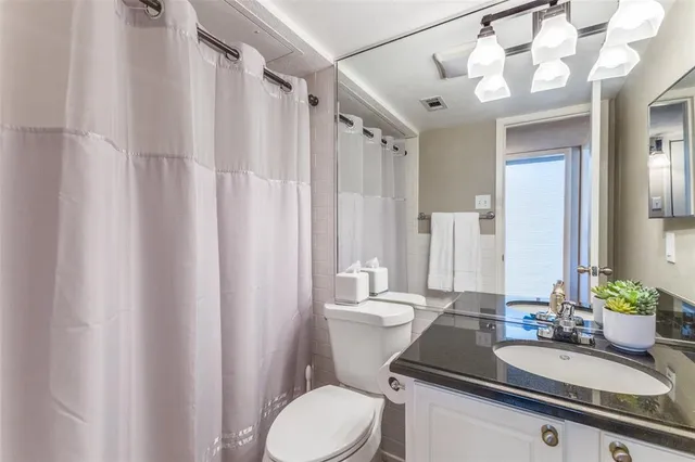 a bathroom with a granite countertop sink mirror vanity and toilet