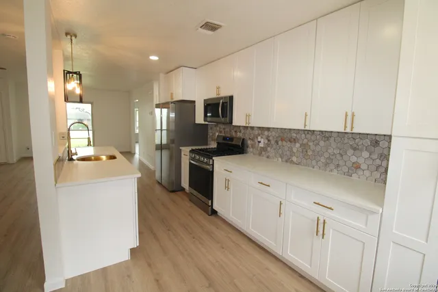 a kitchen with kitchen island white cabinets and stainless steel appliances
