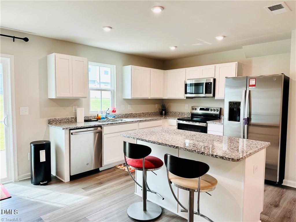 6840 Tarik Lane Raleigh, NC 27610 - Photo 7 of 27 a kitchen with stainless steel appliances granite countertop a stove a sink a refrigerator a microwave and white cabinets