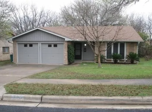 a view of a house with a yard and large tree