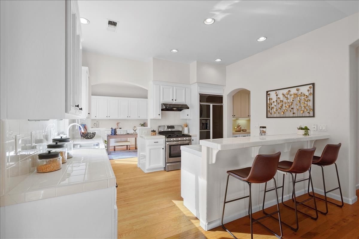 2144 Gullane Way Gilroy, CA 95020 - Photo 7 of 22 a large white kitchen with stainless steel appliances granite countertop a stove a sink a dining table and chairs