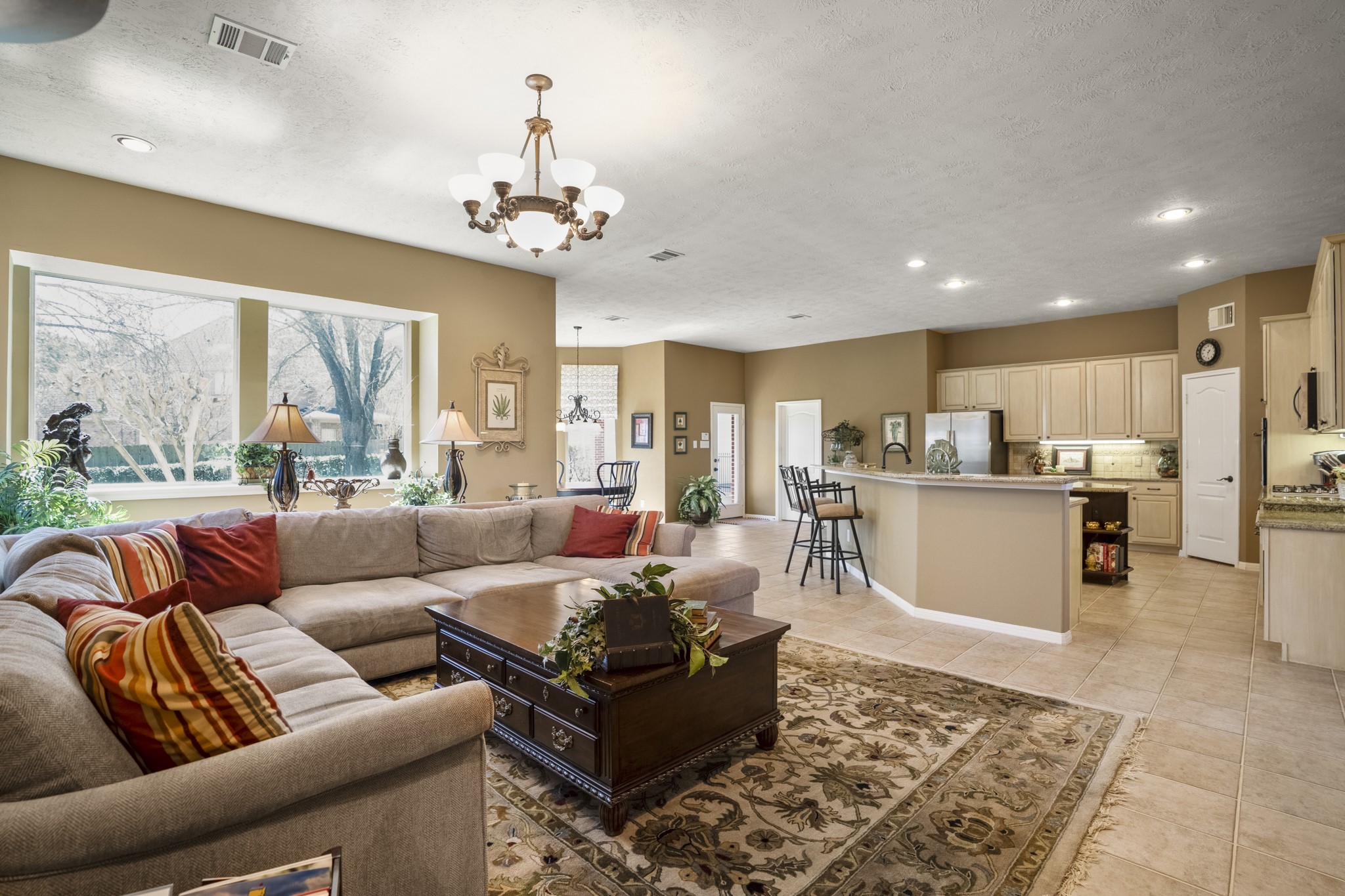 6615 Haughton Drive Spring, TX 77389 - Photo 11 of 50 From this angle, the main living area opens up beautifully. The large window along the back wall draws in natural light and offers a clear view of the backyard, brightening both the family room and kitchen throughout the day. The island sits at the center, an easy gathering place whether meals are being prepped or conversations are unfolding nearby.