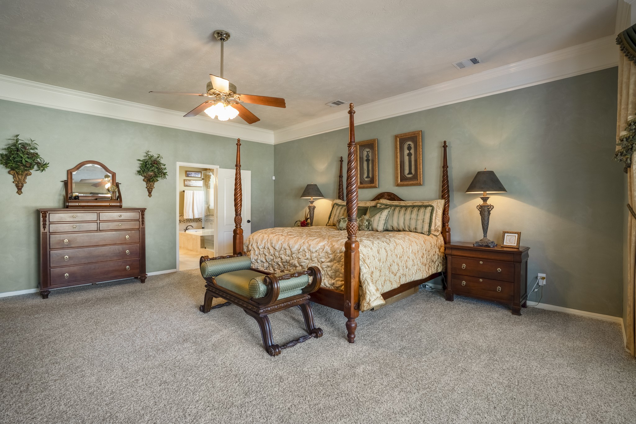 6615 Haughton Drive Spring, TX 77389 - Photo 19 of 50 From this angle, the primary suite feels settled and quiet. With the bay windows just behind us, natural light carries through the room during the day, while the space itself allows for a slower pace at night. Crown moulding adds a subtle finish overhead, and through the doorway, you catch a glimpse of the ensuite bath — the retreat continuing just beyond.