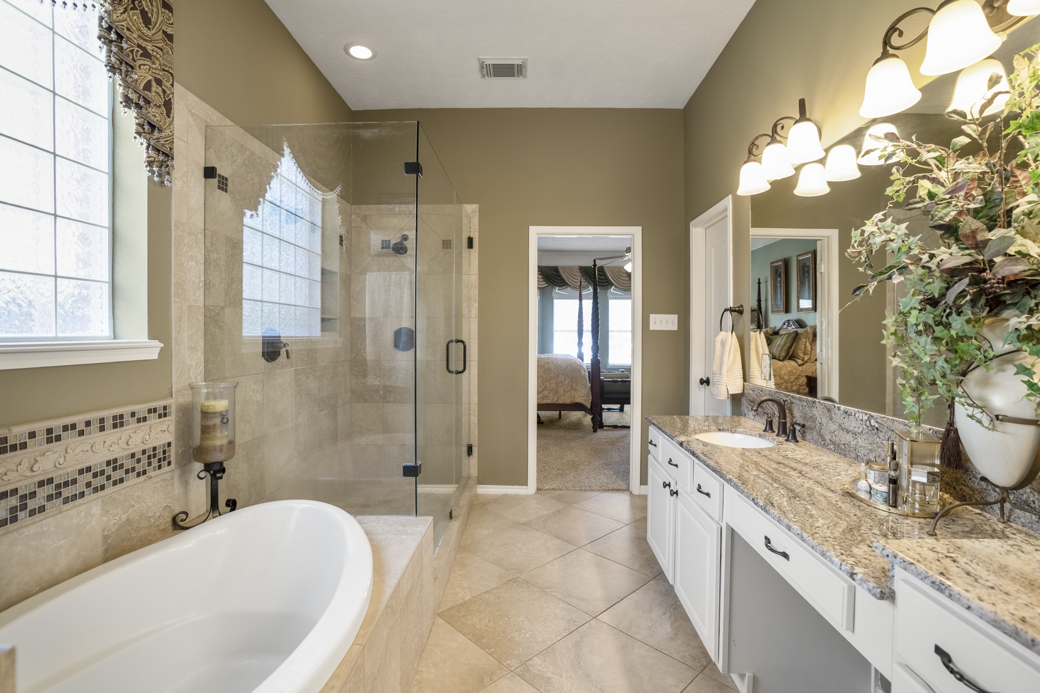 6615 Haughton Drive Spring, TX 77389 - Photo 22 of 50 From this angle, the full length of the vanity comes into focus. Dual sinks are set at each end, with added counter space and a dedicated vanity area between them — giving each side its own room to spread out. The granite counters and expansive mirrors keep the space feeling bright and polished.
Across the room, we get another look at the frameless glass shower, reinforcing the elevated feel that carries throughout the bath.