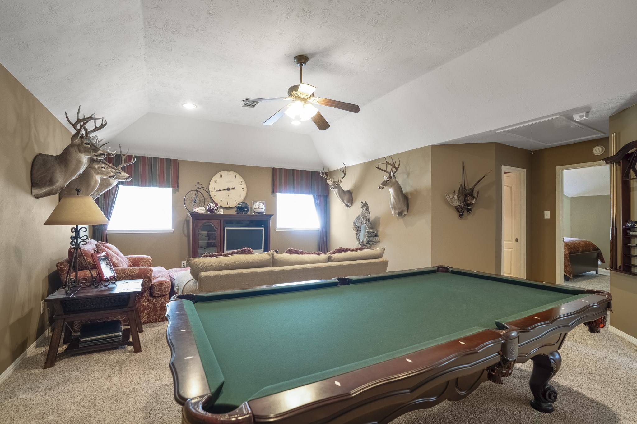 6615 Haughton Drive Spring, TX 77389 - Photo 25 of 50 At the top of the stairs, the upstairs living area opens into a generous game room. With plenty of space for a full-size pool table and additional seating, this level creates a natural spot for recreation, movie nights, or simply spreading out. The ceiling fan keeps air moving comfortably, and the layout allows this space to feel separate from the bedrooms while still easily accessible.
