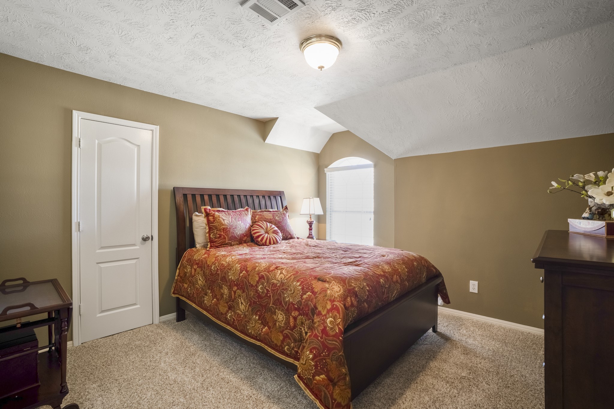 6615 Haughton Drive Spring, TX 77389 - Photo 29 of 50 The first of three upstairs bedrooms continues the home’s light, neutral palette. A vaulted ceiling adds architectural character and gives the room a more open, airy feel, while the large window brings in natural light throughout the day.
