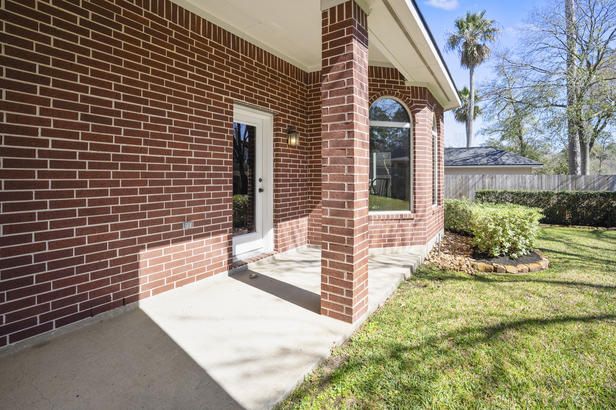 6615 Haughton Drive Spring, TX 77389 - Photo 36 of 50 Stepping outside, the covered back patio offers a shaded spot to relax while overlooking the backyard. Brick columns frame the space, and there’s room here for outdoor seating or a grill setup. It’s an easy extension of the home — simple, open, and ready for quiet evenings or casual gatherings.