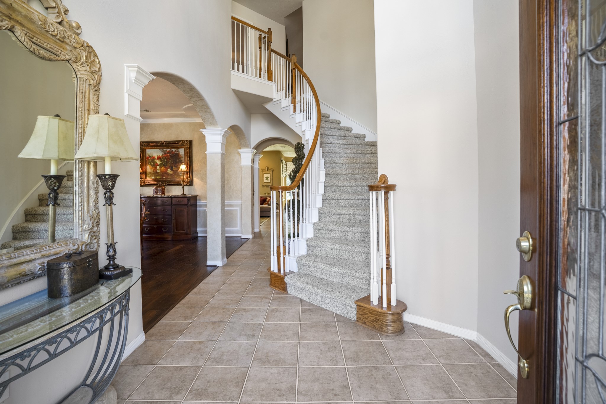 6615 Haughton Drive Spring, TX 77389 - Photo 4 of 50 Stepping inside, the two-story foyer immediately makes an impression. To the left, arched openings lead into the formal dining room, where the bay window at the front fills the space with natural light. Ahead and slightly to the right, the curved staircase rises gracefully, becoming a focal point of the entry. Just beyond it, another arched opening hints at the living spaces tucked further into the home — giving you a preview without revealing everything at once.
Let’s start by stepping into the dining r