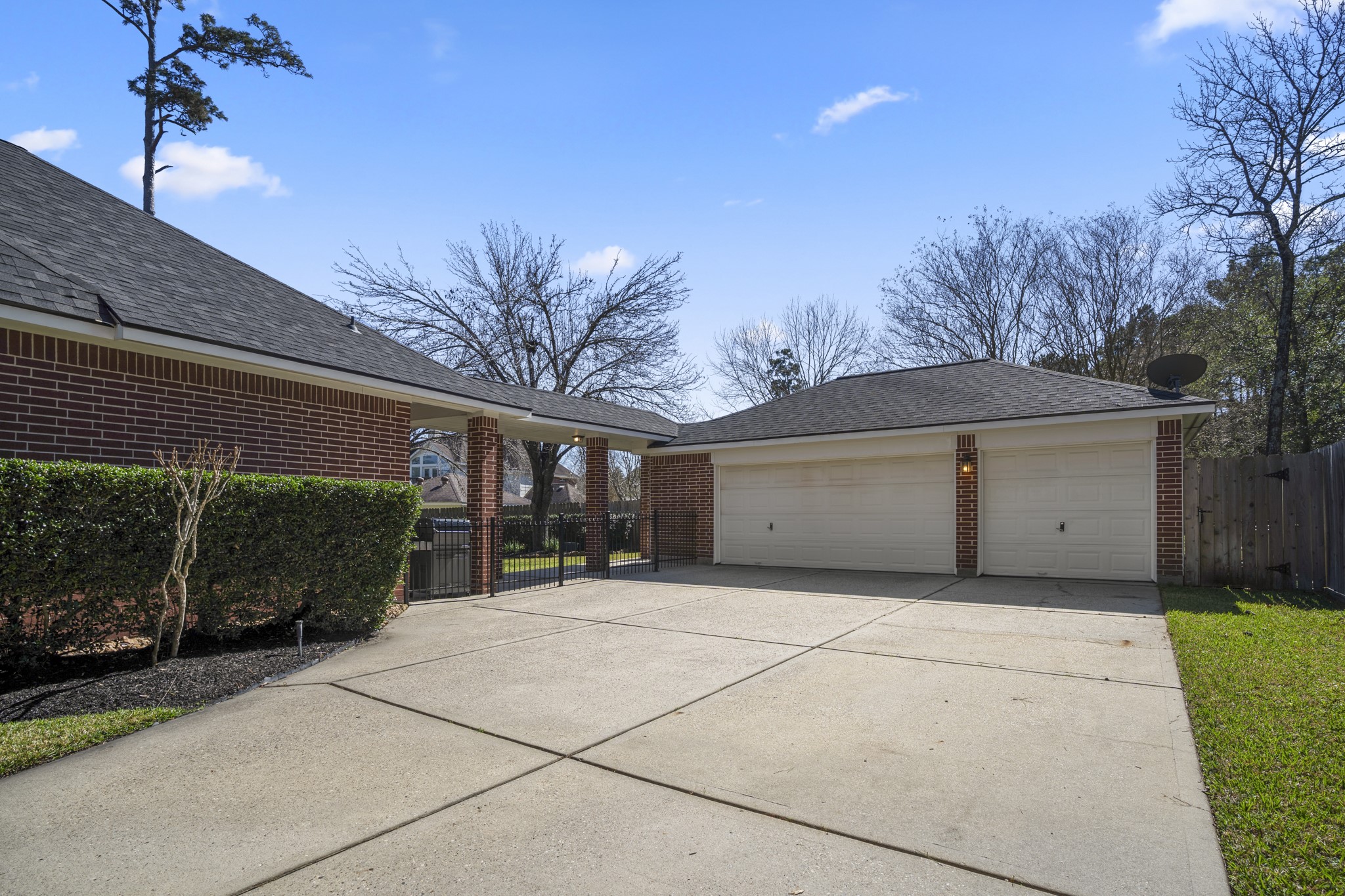 6615 Haughton Drive Spring, TX 77389 - Photo 43 of 50 Moving through the driveway gate and stepping back, the detached three-car garage comes fully into view. Set behind the home and connected by the covered breezeway, it offers ample parking and storage while keeping the front elevation clean and uninterrupted. The extended driveway provides additional space for guests or everyday convenience.