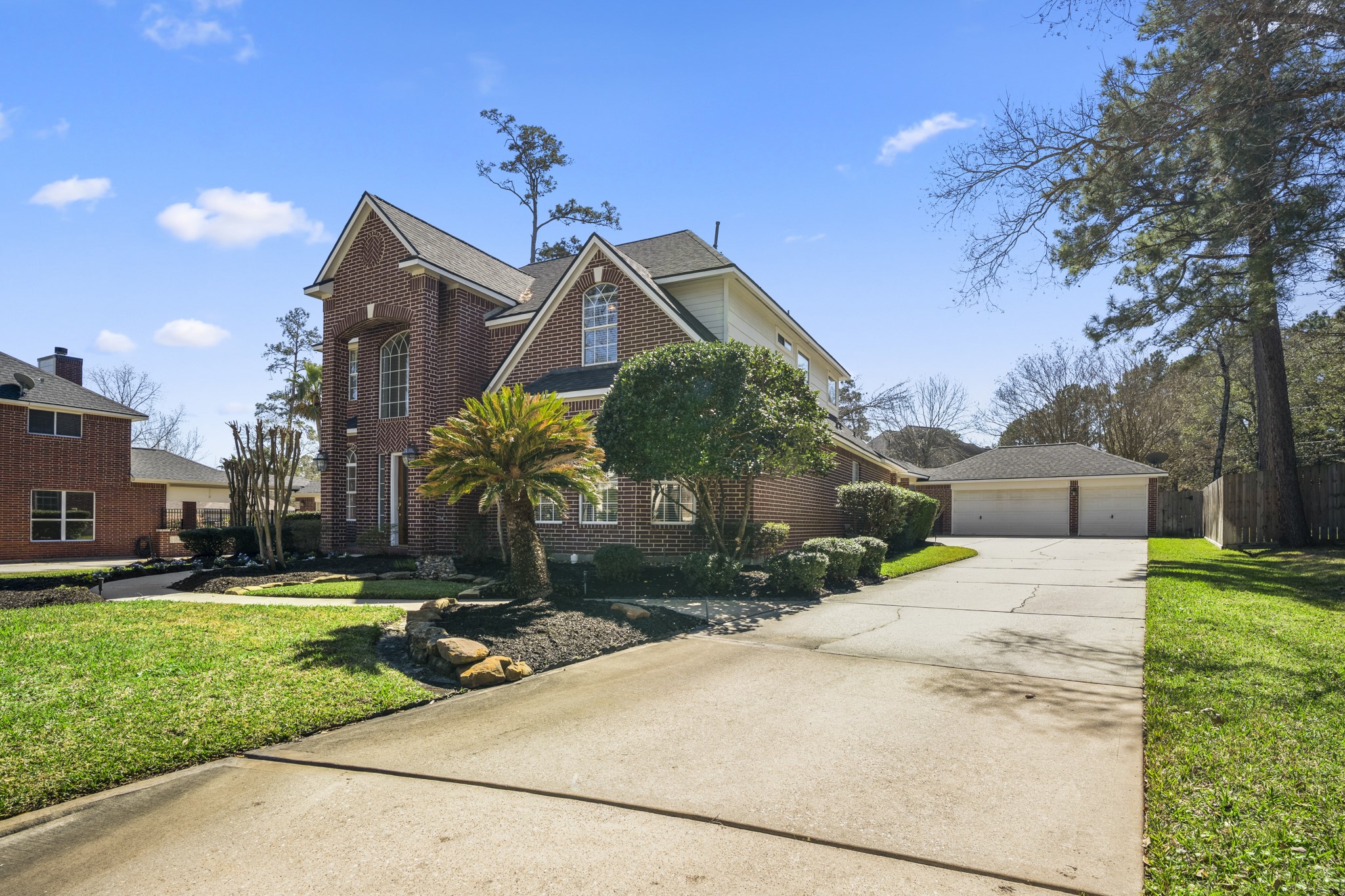 6615 Haughton Drive Spring, TX 77389 - Photo 44 of 50 Moving back down the driveway toward the street, the full front elevation comes back into view. Mature trees frame the home, and the brick façade, arched windows, and clean rooflines create a timeless first impression. From this angle, you can appreciate the spacious cul-de-sac lot and how the detached garage sits thoughtfully behind the home.