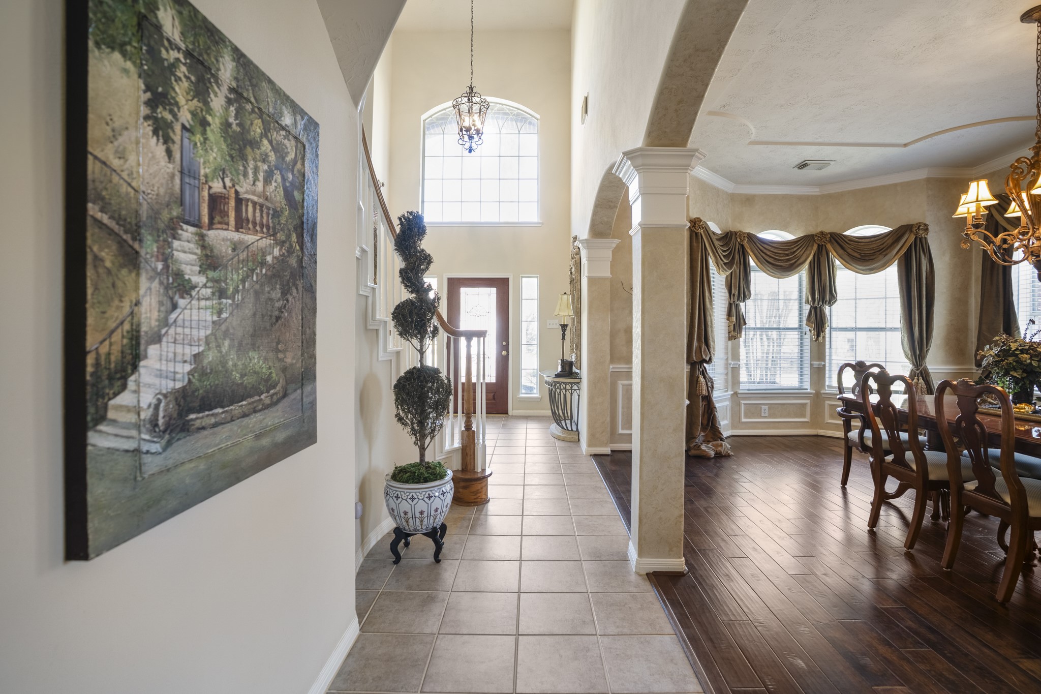6615 Haughton Drive Spring, TX 77389 - Photo 5 of 50 Moving past the staircase, we pause and look back toward the front door. From this vantage point, the height of the foyer feels even more dramatic, with natural light pouring in from the arched window above the entry. To the right, the formal dining room now opens fully into view through the arched columns, its rich flooring and front bay window giving it warmth and depth. Behind us sits the family room, quietly tucked beyond the foyer — but first, let’s step into the dining room for a closer look.