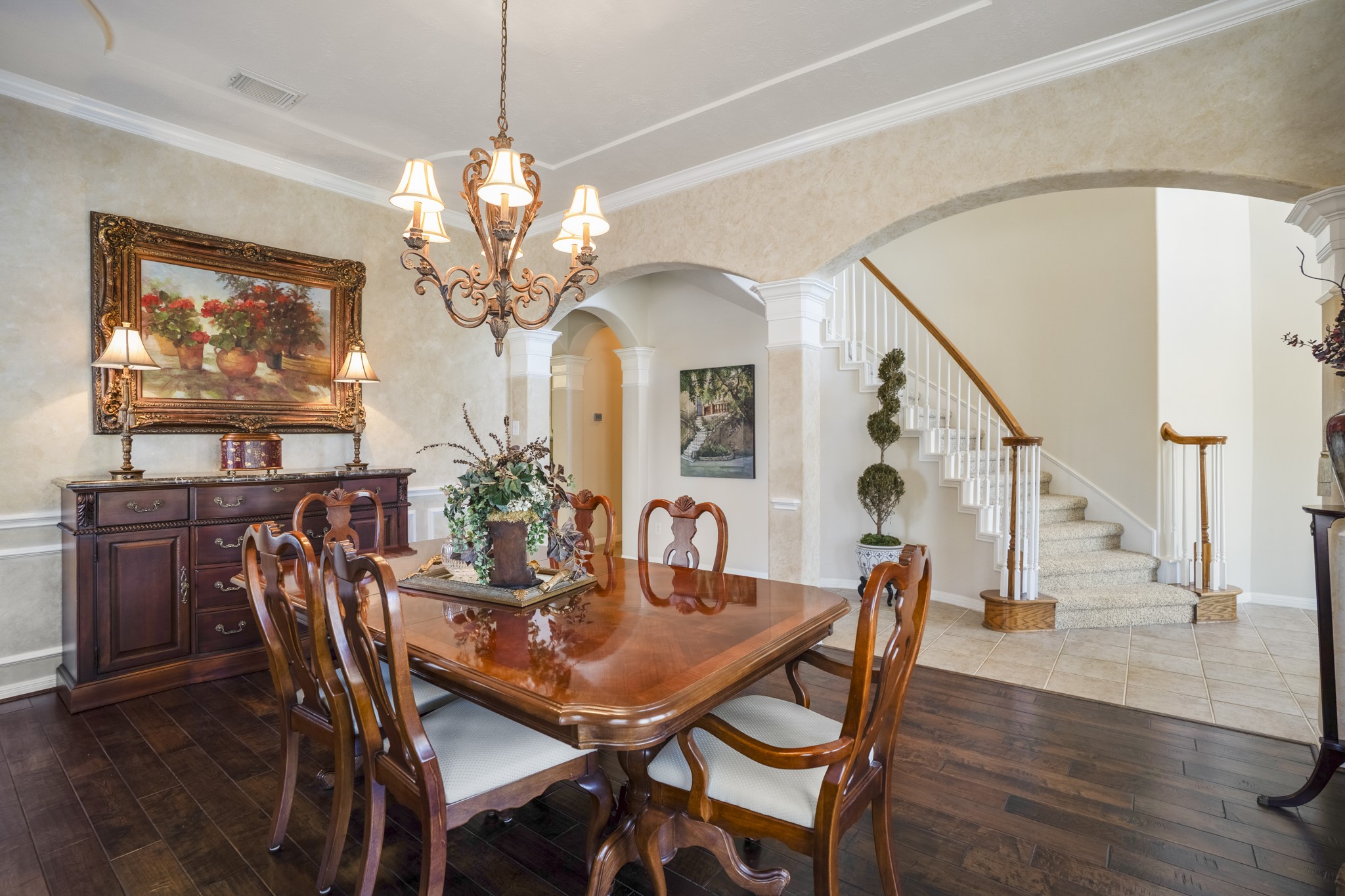 6615 Haughton Drive Spring, TX 77389 - Photo 7 of 50 From this angle, you can see how the dining room connects back to the entry. The curved staircase becomes part of the backdrop, framed by the arched opening and detailed trim work. The openness keeps the room feeling connected while still giving it its own defined presence.
Rich wood flooring anchors the dining space, transitioning to tile as you move back into the foyer — a subtle distinction that helps define each area while maintaining flow.