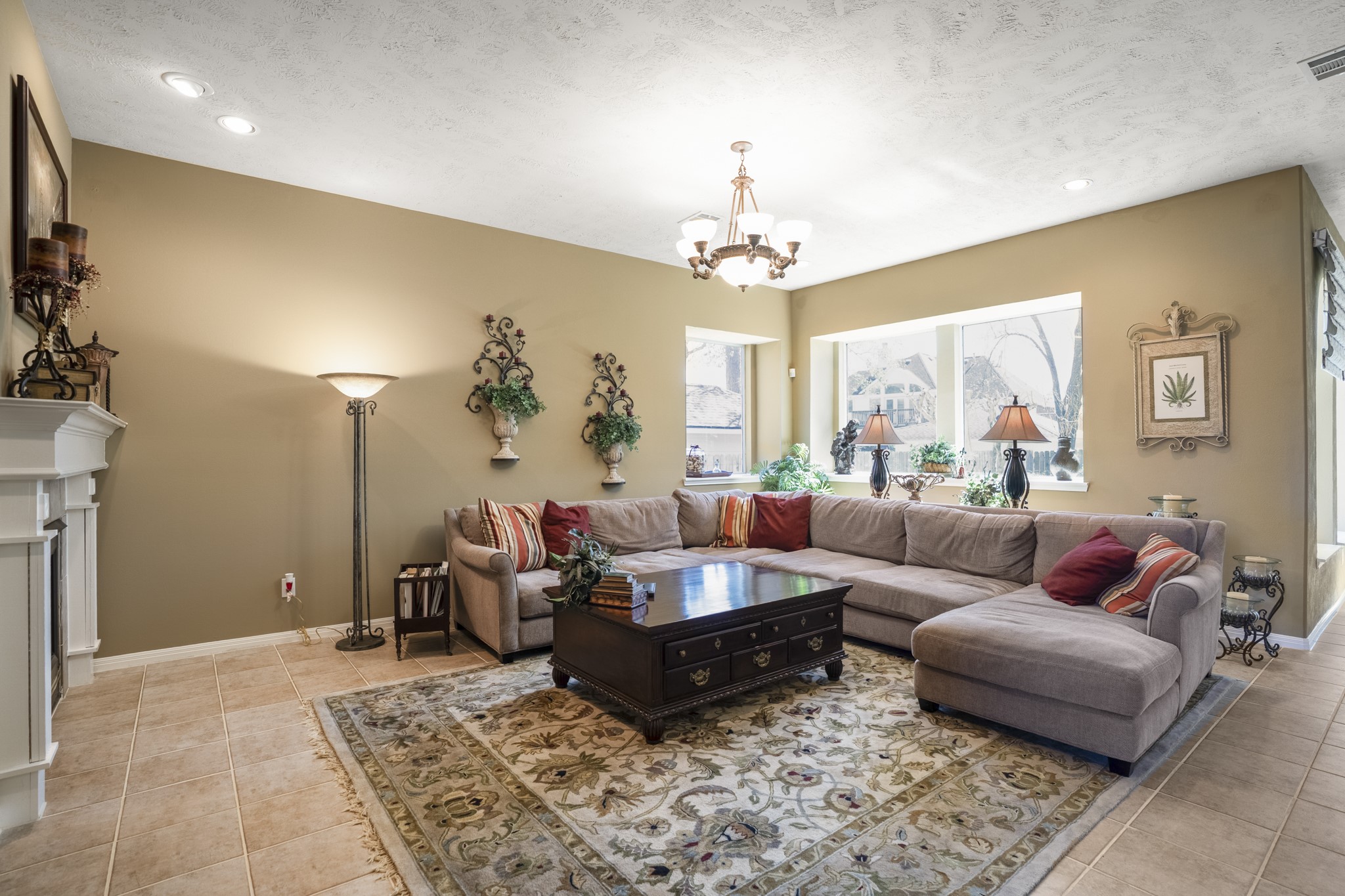 6615 Haughton Drive Spring, TX 77389 - Photo 8 of 50 Continuing forward, we arrive in the family room — a welcoming space centered around the fireplace and framed by windows along the back of the home. Natural light filters in from the backyard, giving the room a relaxed, everyday feel. Tile flooring keeps it practical and easy to maintain, while the layout allows for comfortable seating and conversation.
