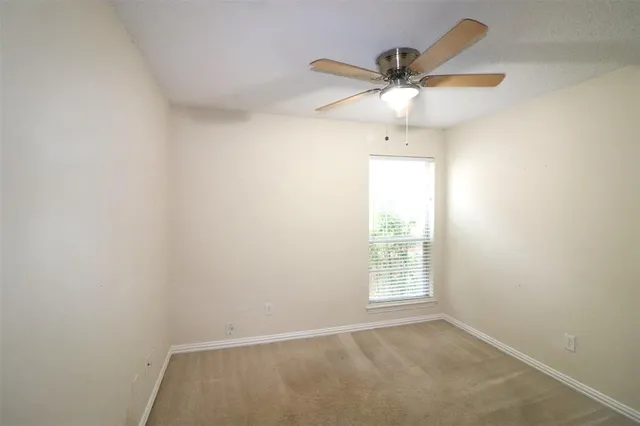 an empty room with a window and a ceiling fan