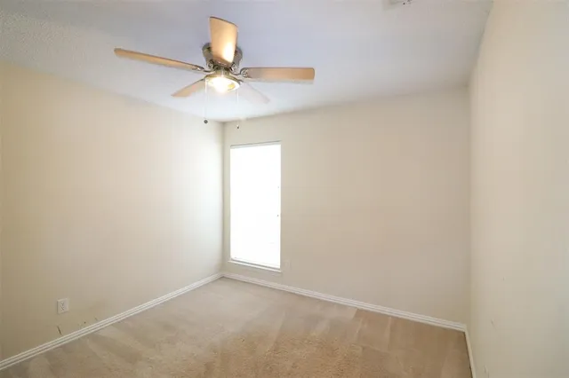 an empty room with a window and a fan