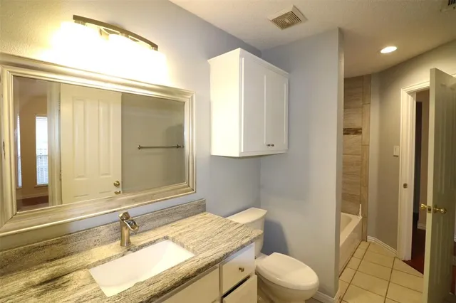 a bathroom with a granite countertop sink mirror vanity and toilet