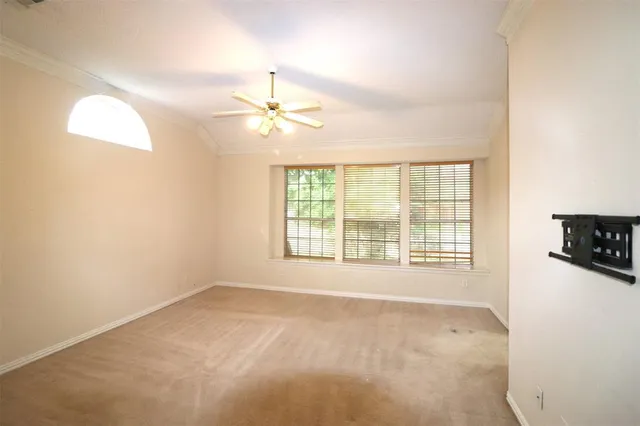 an empty room with chandelier fan and windows