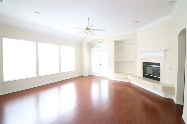 an empty room with wooden floor fireplace and windows