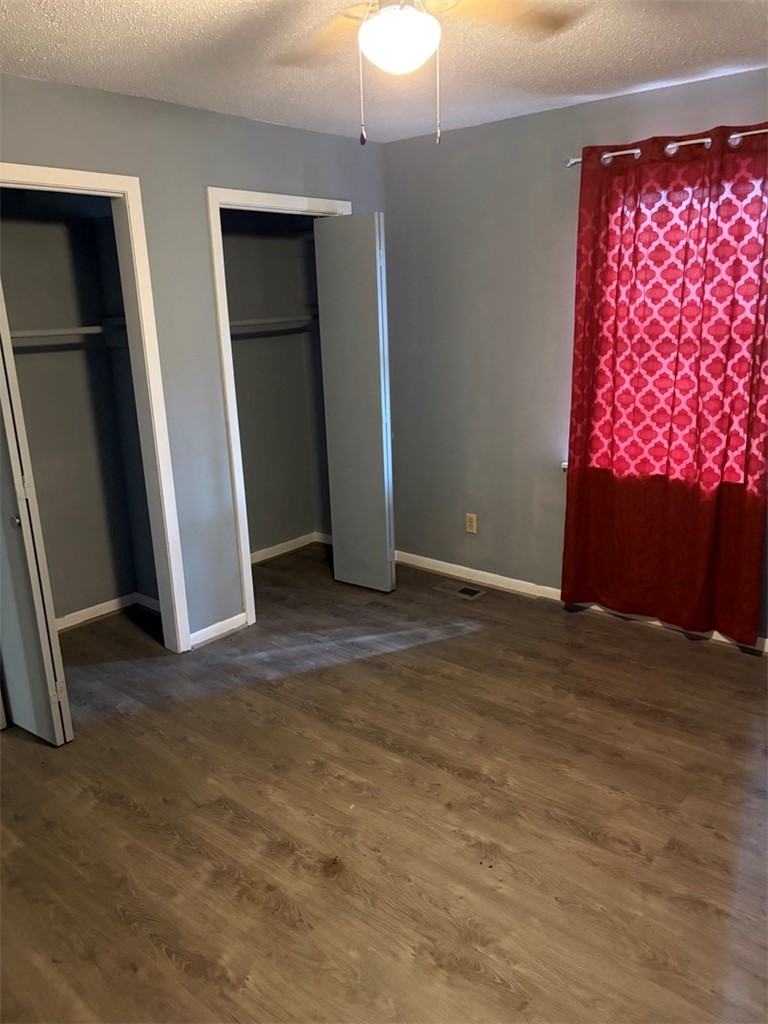 618 Madden Road Jacksonville, AR 72076 - Photo 31 of 34 Bedroom featuring wood-finish flooring, two open closet entries with interior hanging rods, light gray wall paint, and a ceiling fan with integrated lighting