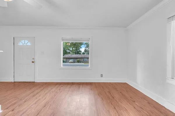 a view of an empty room with wooden floor and a window