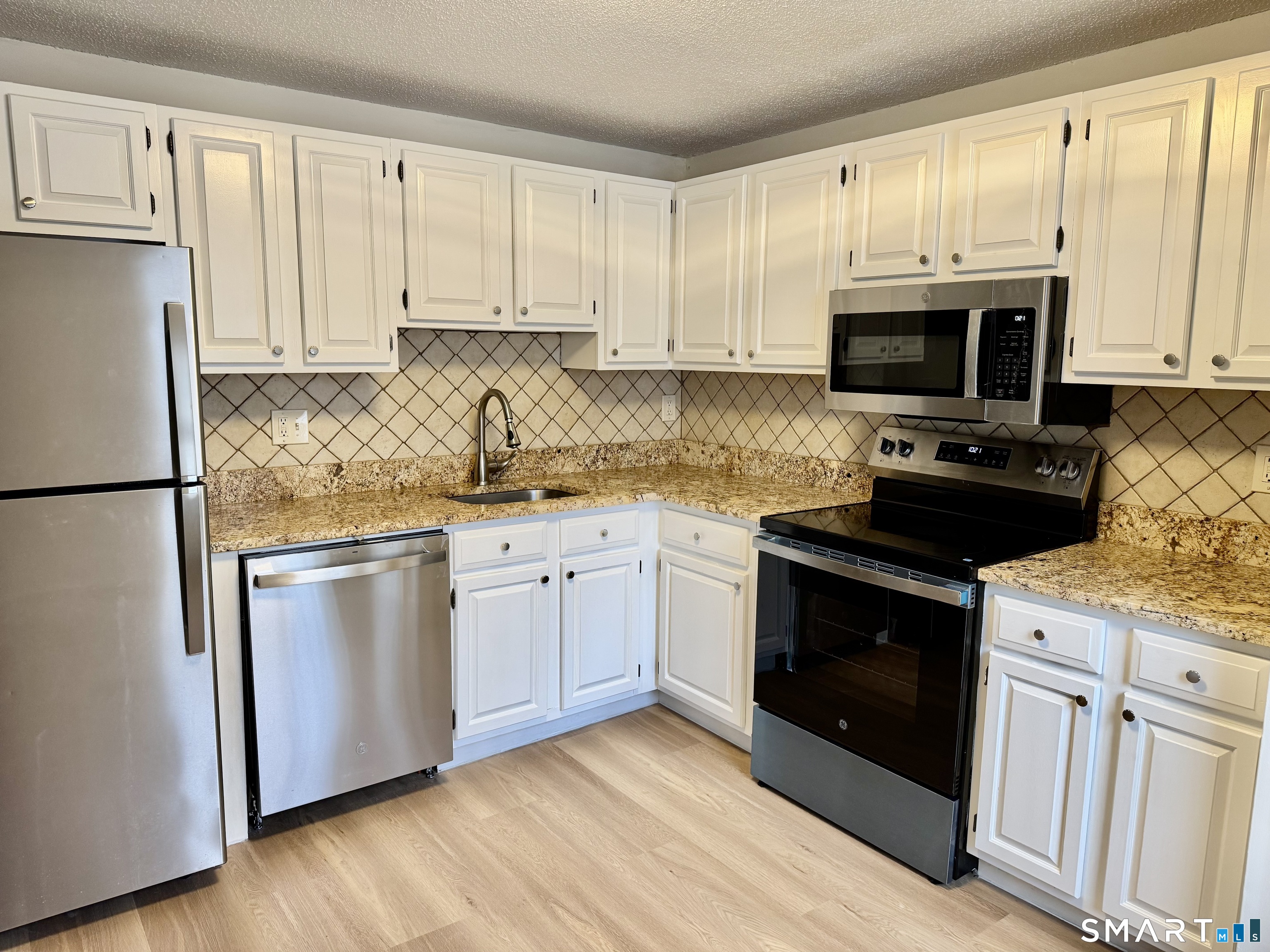 8 Heather Ridge, Unit 8 Shelton, CT 06484 - Photo 3 of 13 a kitchen with granite countertop white cabinets sink and stainless steel appliances
