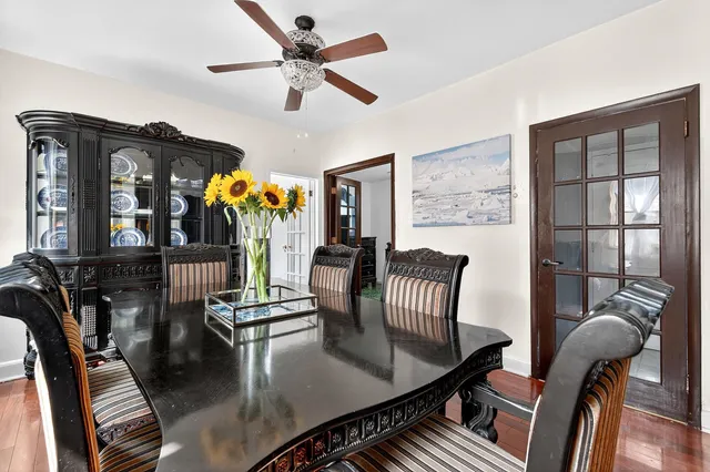 a kitchen with stainless steel appliances granite countertop a sink a stove a dining table and chairs with wooden floor