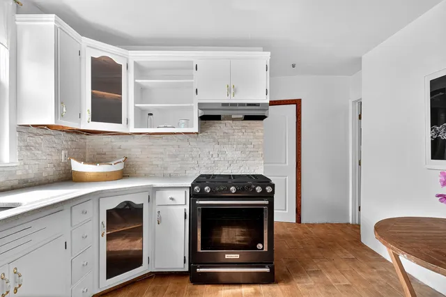 a kitchen with granite countertop stainless steel appliances a stove a sink dishwasher and cabinets with wooden floor