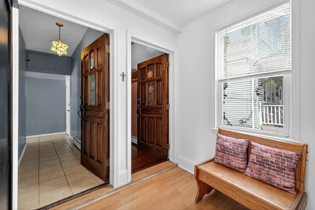a view of a hallway and a livingroom with wooden floor and windows