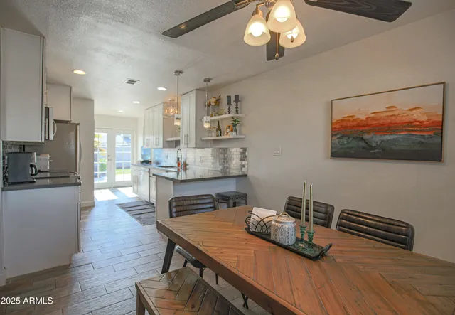 a kitchen with stainless steel appliances granite countertop a stove a refrigerator a sink a dining table and chairs with wooden floor