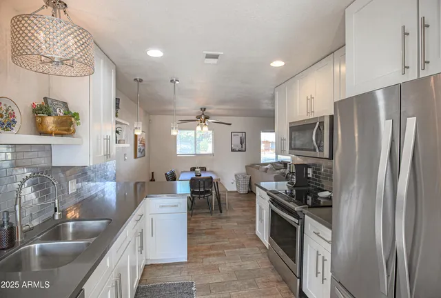 a kitchen with stainless steel appliances kitchen island granite countertop a refrigerator and a sink