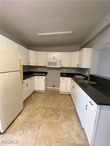 a kitchen with granite countertop a sink a stove and refrigerator