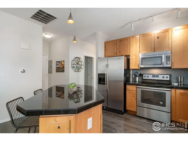 a kitchen with stainless steel appliances granite countertop a sink a stove and a refrigerator