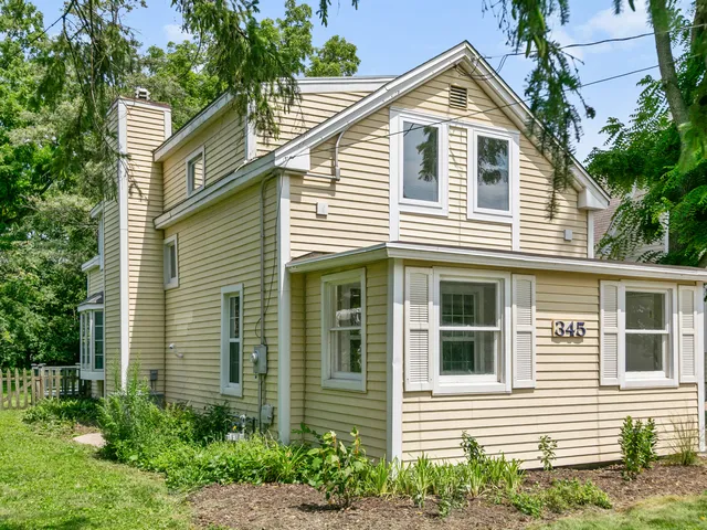 a view of a white house next to a yard